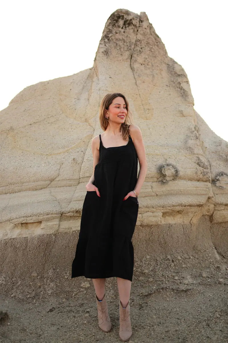 Woman in a black Spaghetti Strap dress standing in front of a rock formation