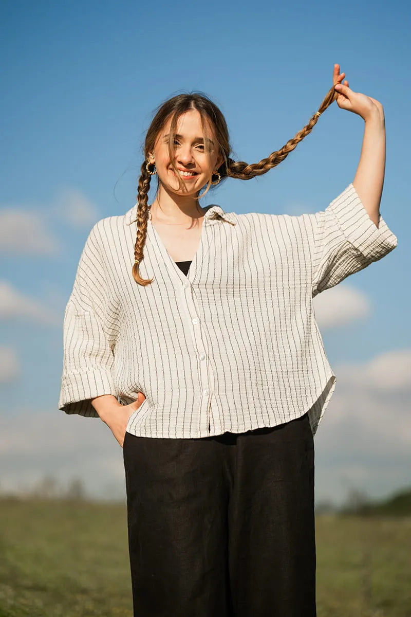 Woman with striped shirt standing outdoors against a blue sky
