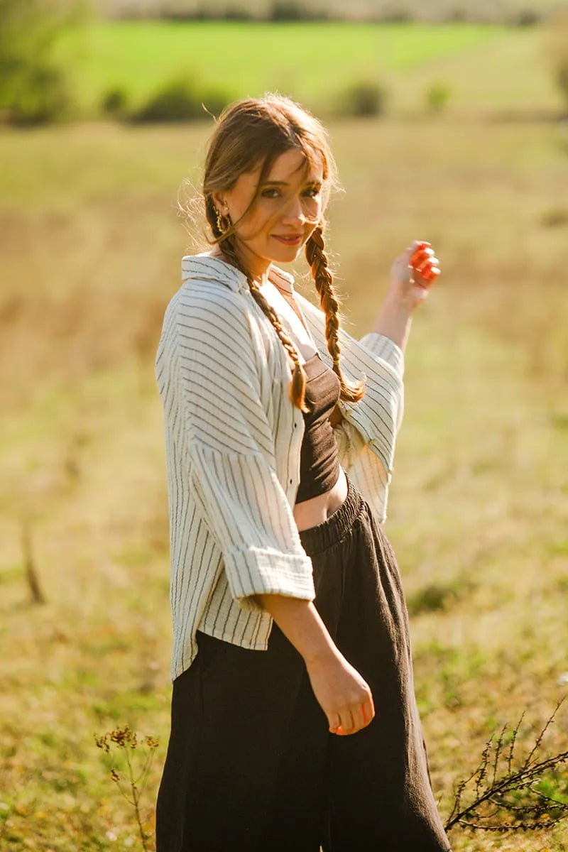 Woman with striped shirt holding a red apple in a field