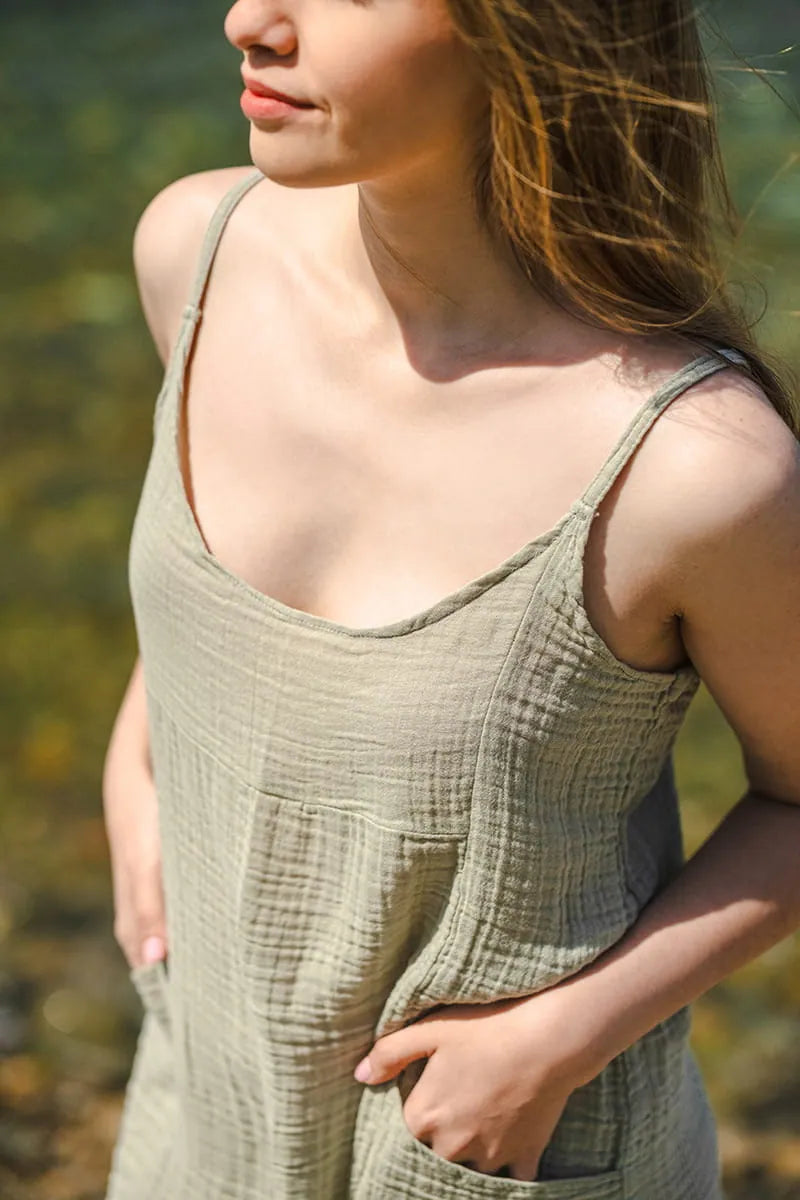 Woman wearing a green sleeveless dress and pants against a blurred natural background