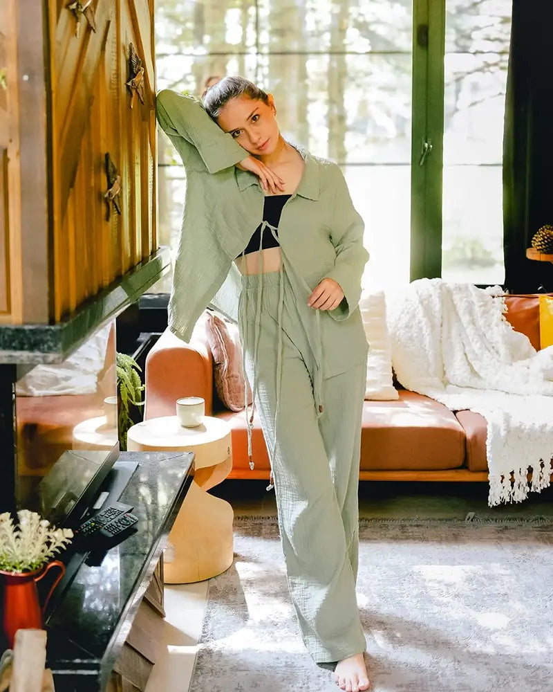 Woman in a green loungewear set is standing in a modern living room.