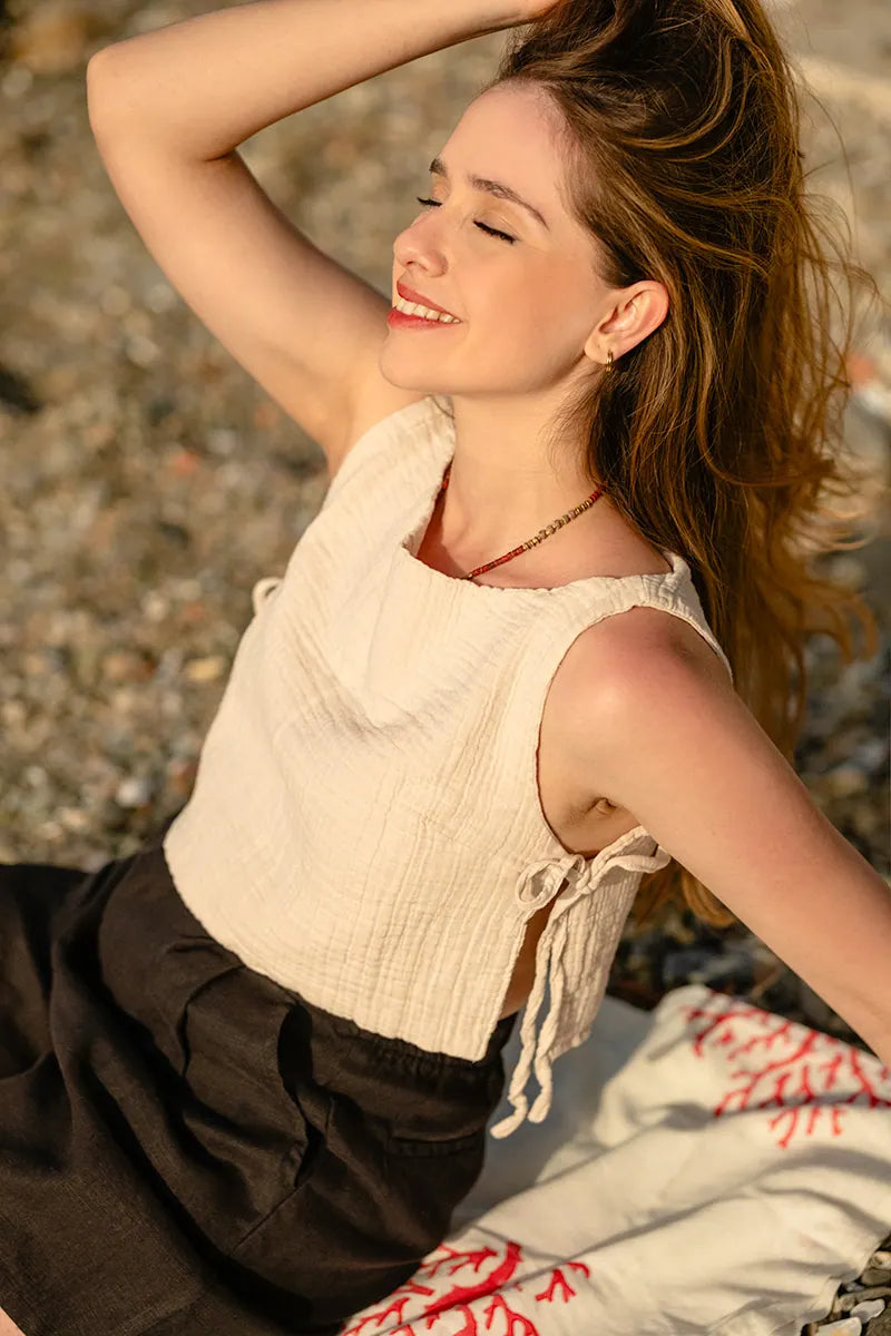 Woman sitting on a beach with a Side Tie Sleeveless Cotton Blouse