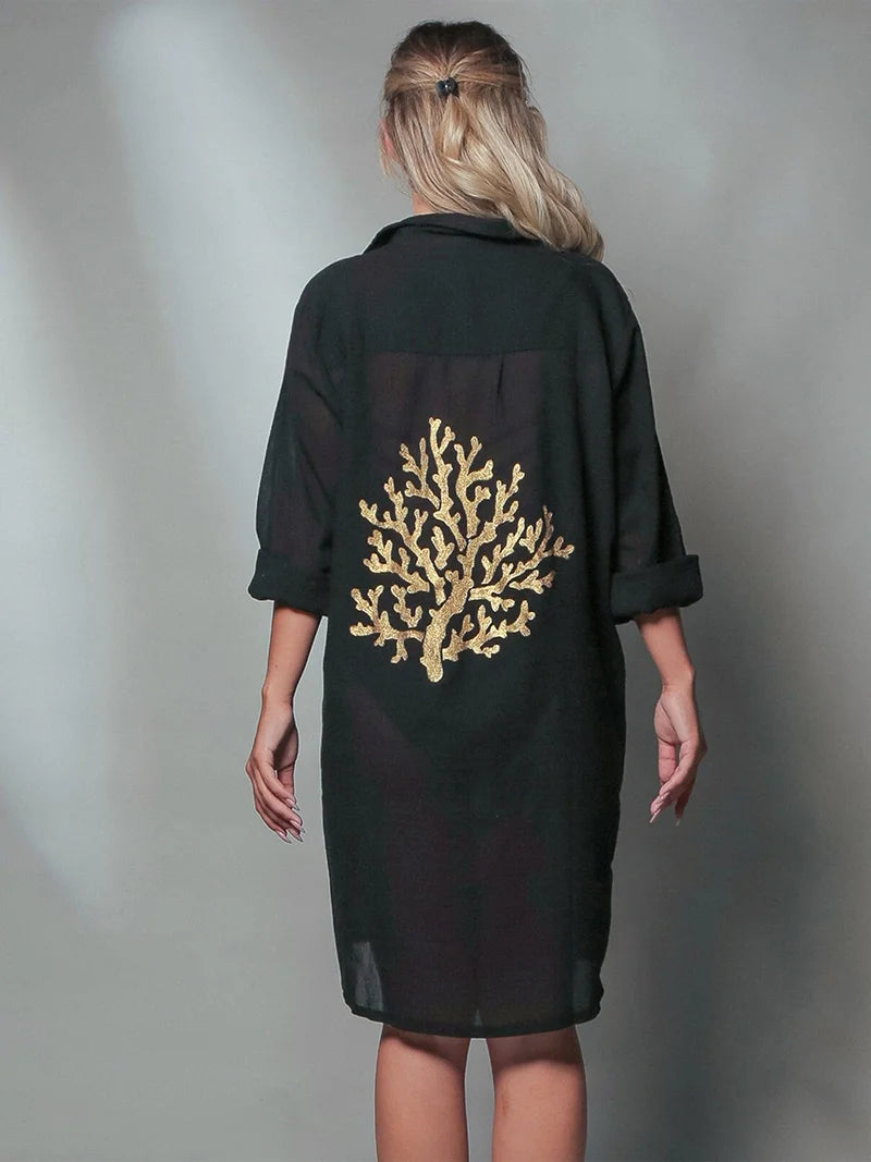 Black dress with gold coral design on the back worn by a model against a gray background