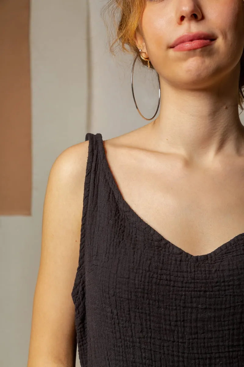 Close-up of a person wearing a black cami dress with a neutral background