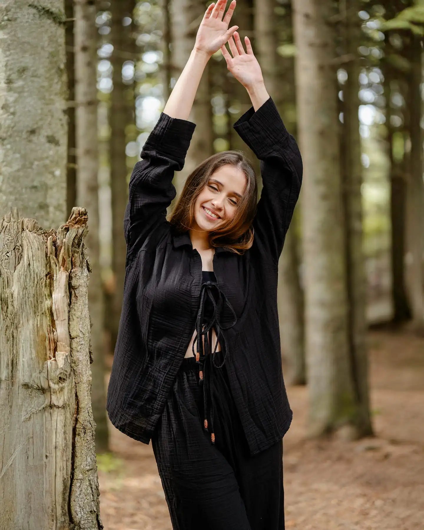 Woman in a black Loungewear Set standing in a forest with trees in the background