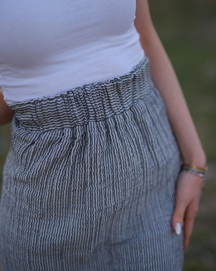 A close up picture of woman wearing white top and a long gauze maxi skirt.