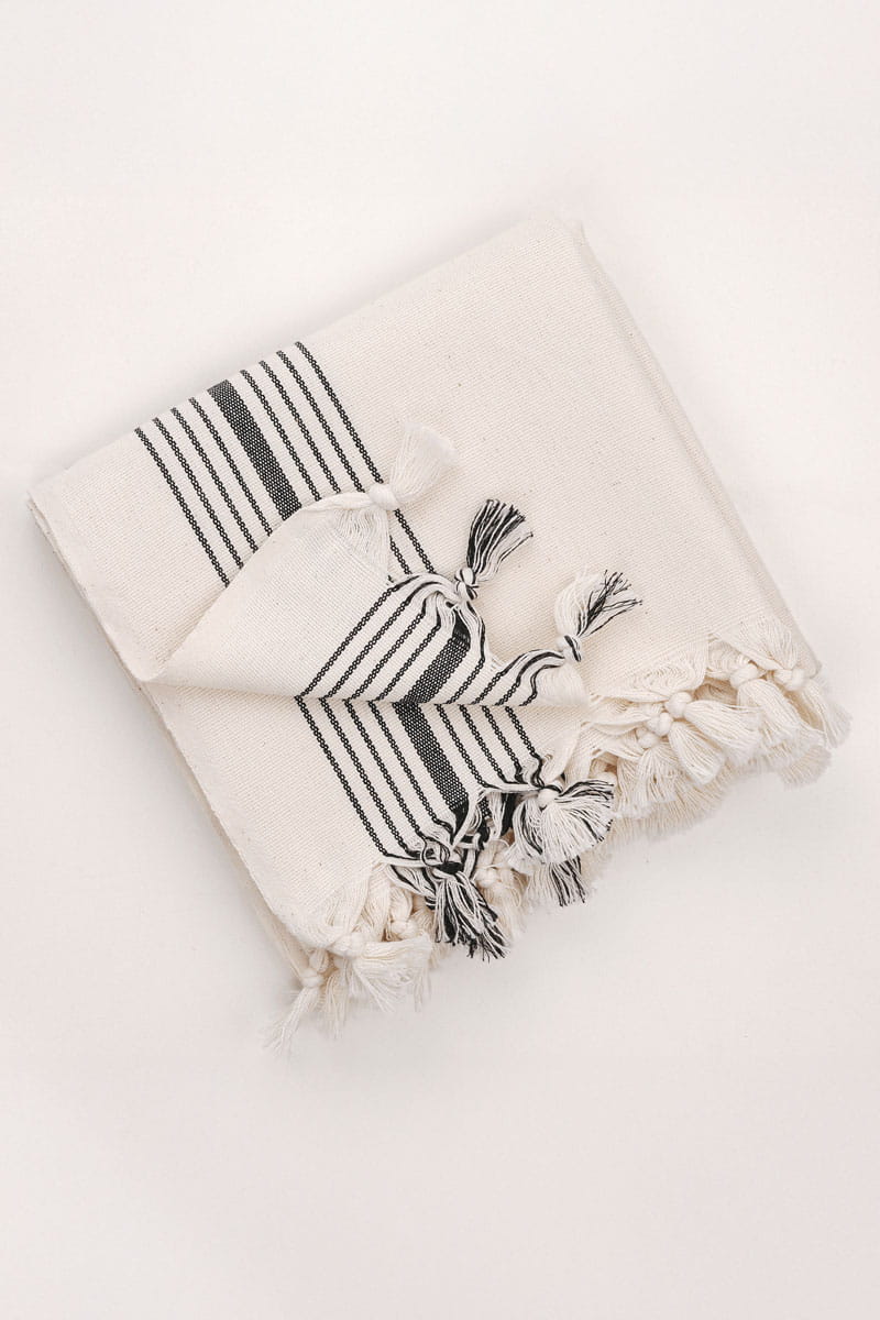 Neatly folded Turkish cotton bath towel with tassel trim on a light surface