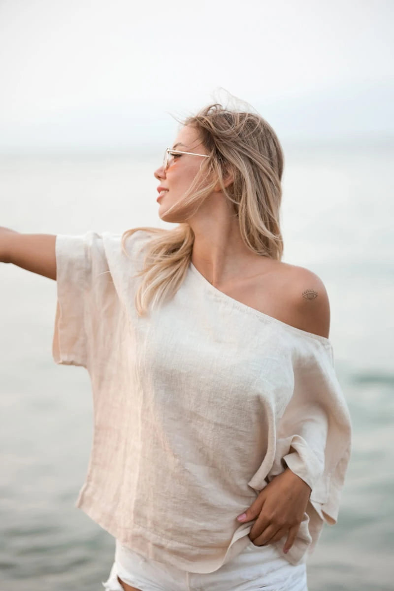 Woman in a beige linen tshirt standing on a beach