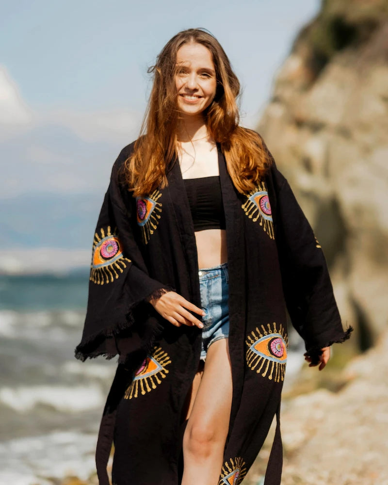 Woman wearing a black kimono with celestial evil eye pattern by the beach