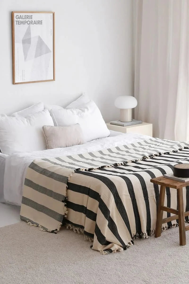 Bedroom with a striped blanket on a bed, nightstand, and framed picture on the wall.