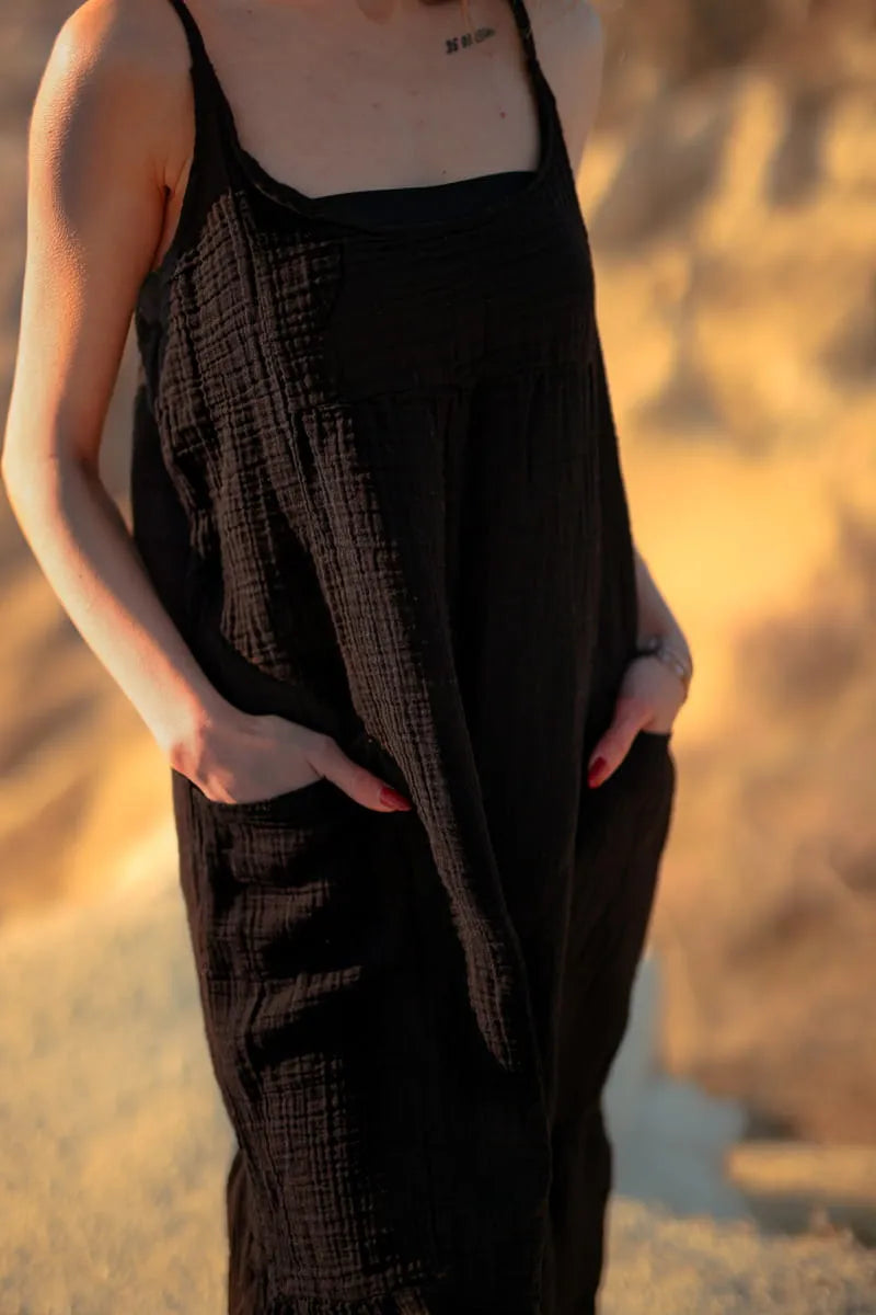 Person wearing a black crinkle cotton texture muslin dress with a blurred natural background
