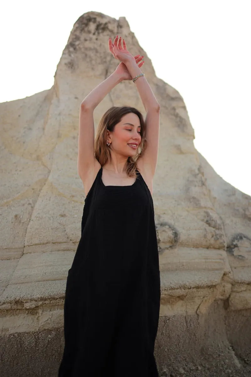 Woman in a black midi dress standing in front of a large stone statue.