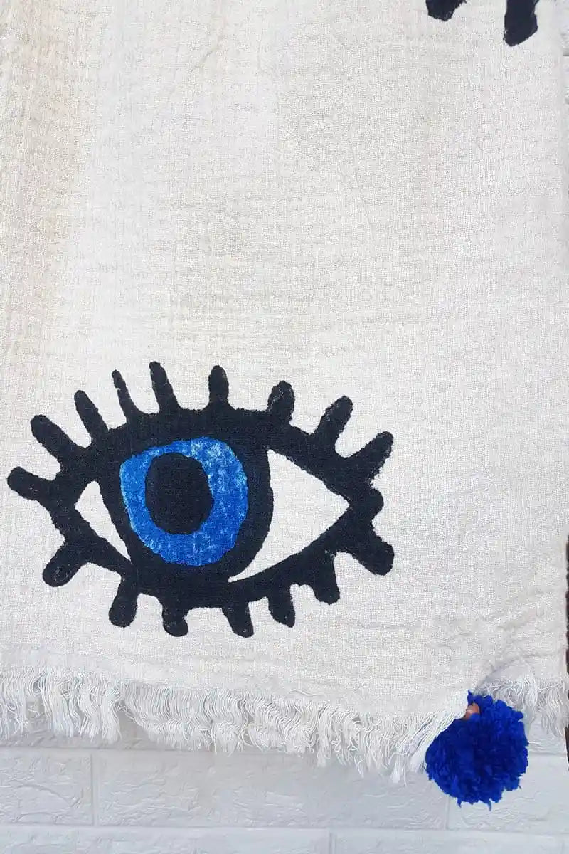 White blanket with a blue and black evil eye design on a white background