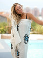 Blue evil eye beach towel wrapped around a woman by a pool — Turkish cotton with blue and black evil eye design