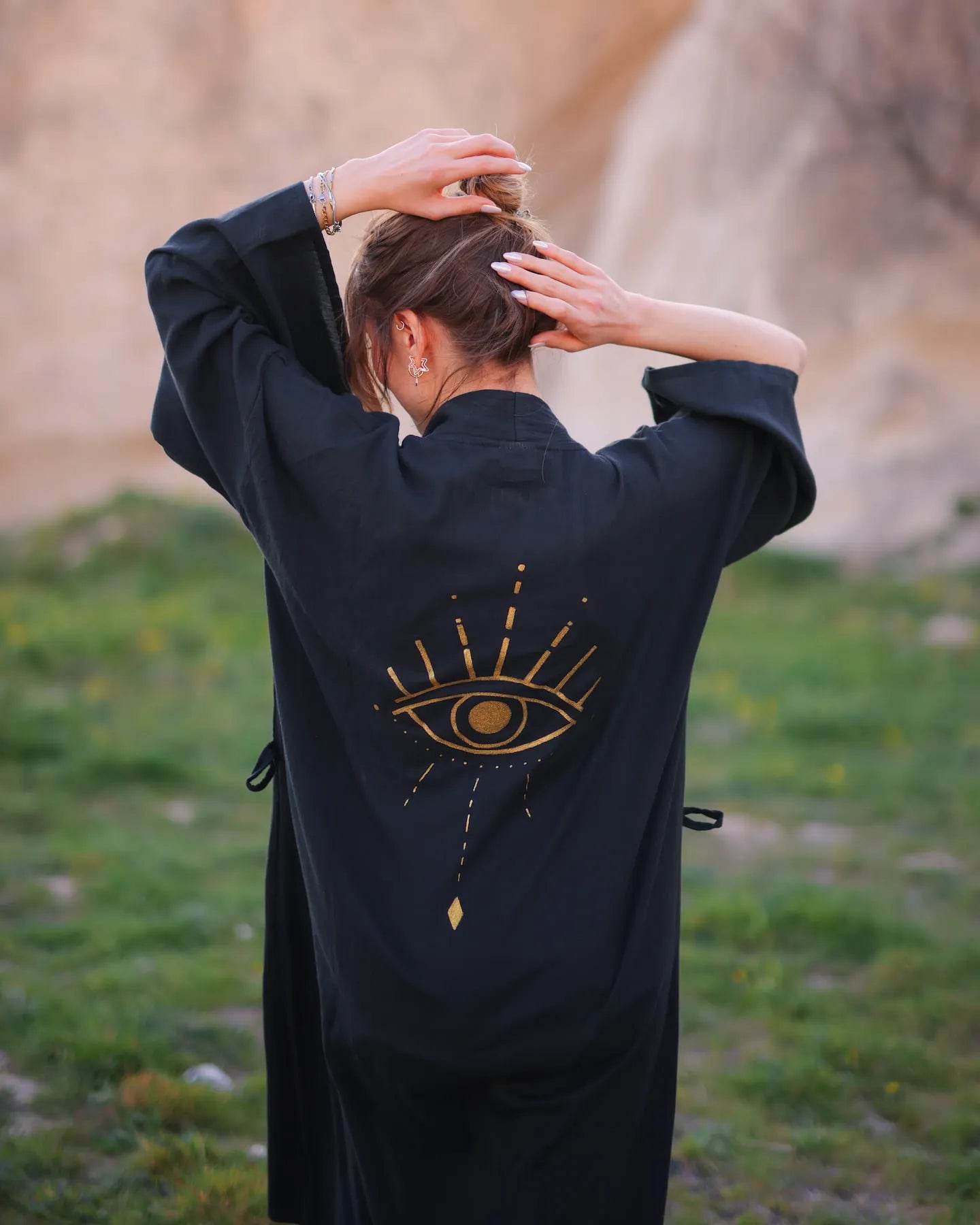 Person wearing a black robe with an eye design outdoors