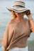 Woman wearing a wide-brimmed hat and beige top by the water