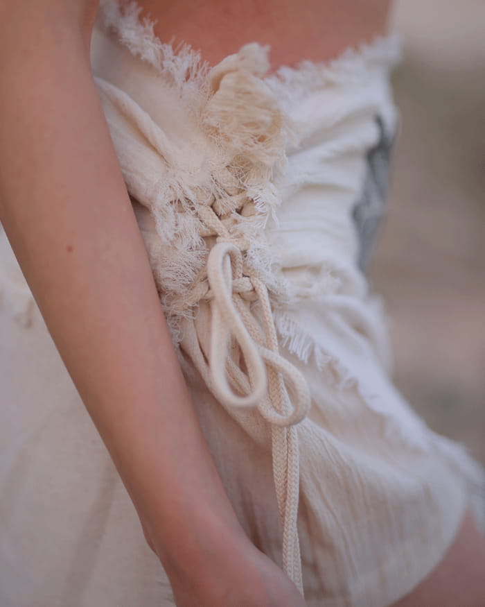 Close-up of a textured white dress with lace details.