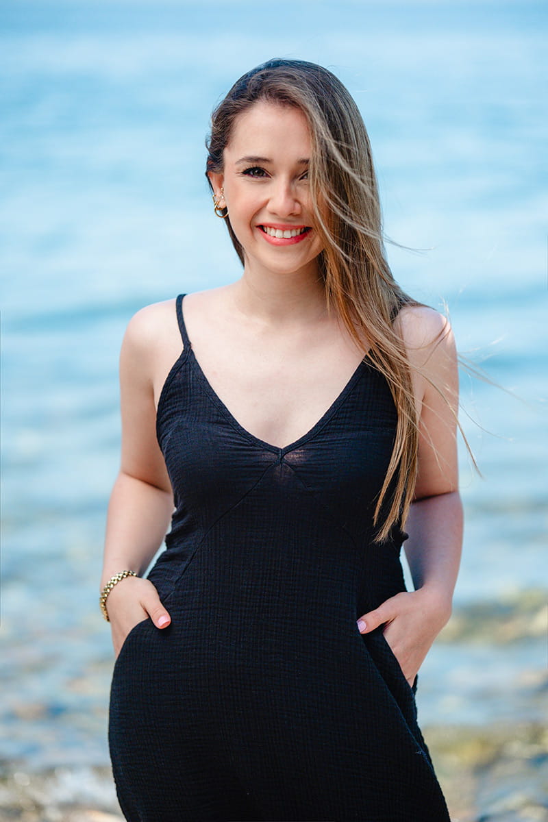 Woman in a black double gauze dress standing by a body of water