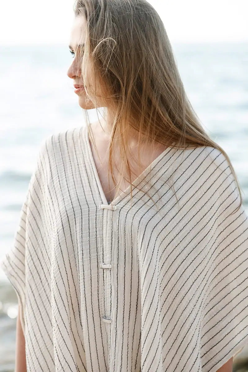 Woman wearing a striped beach cover up by the ocean