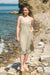 Woman in a Double Gauze Muslin Cotton Strap Midi Dress standing on a rocky beach with ocean in the background