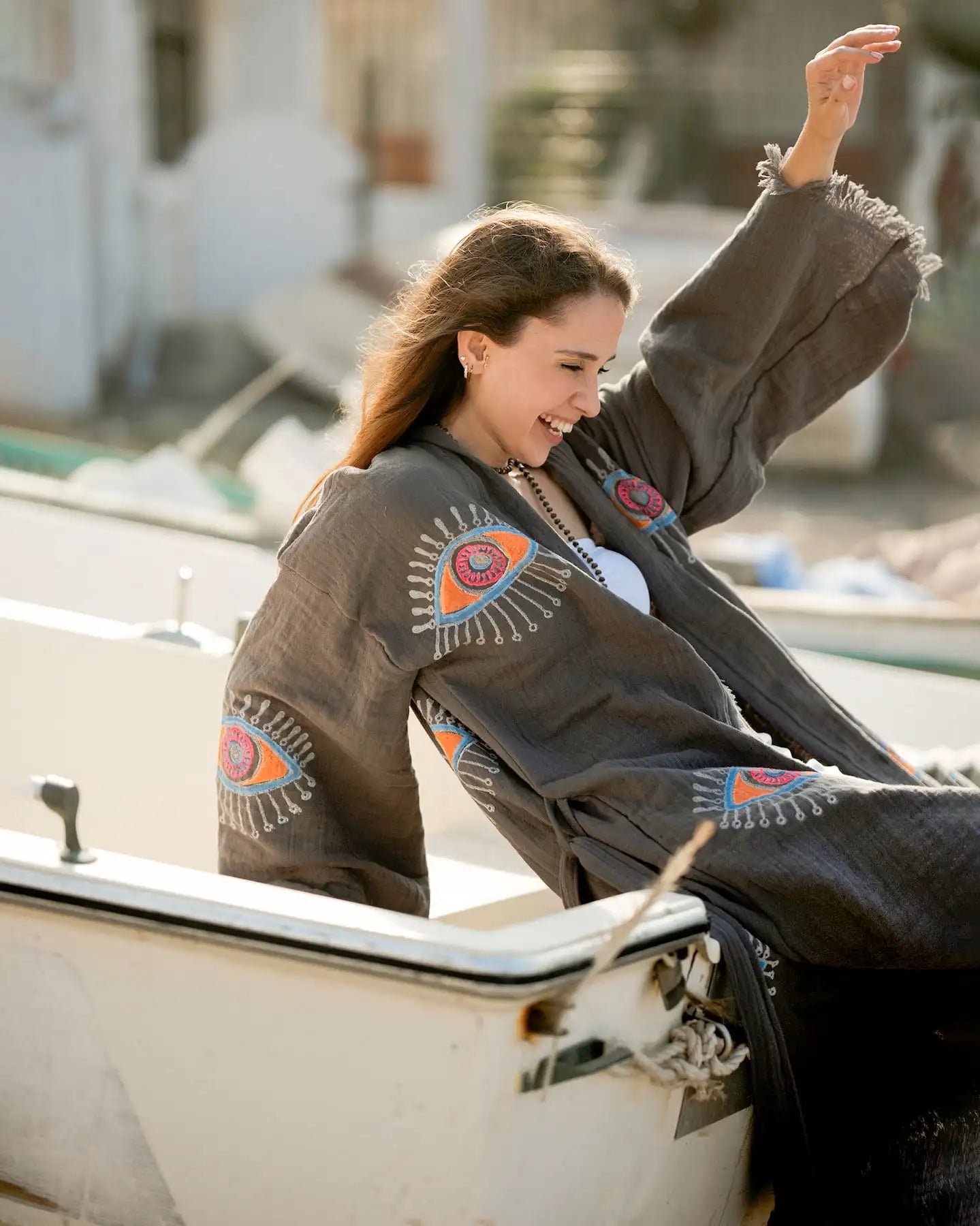 Woman sitting on a boat wearing a evil eye cardigan dress with a blurred background