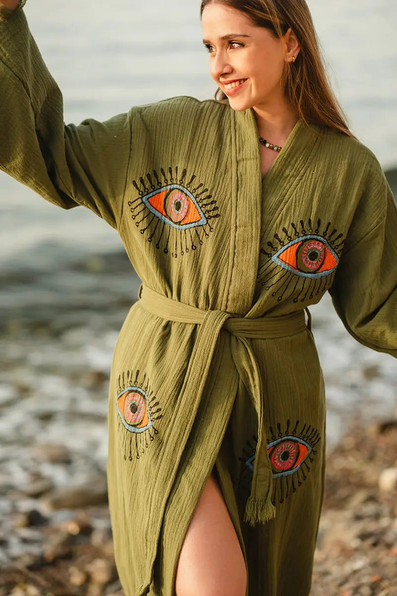 Woman wearing a green evil eye robe by a body of water