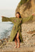 Woman wearing a green evil eye robe  on a rocky beach.