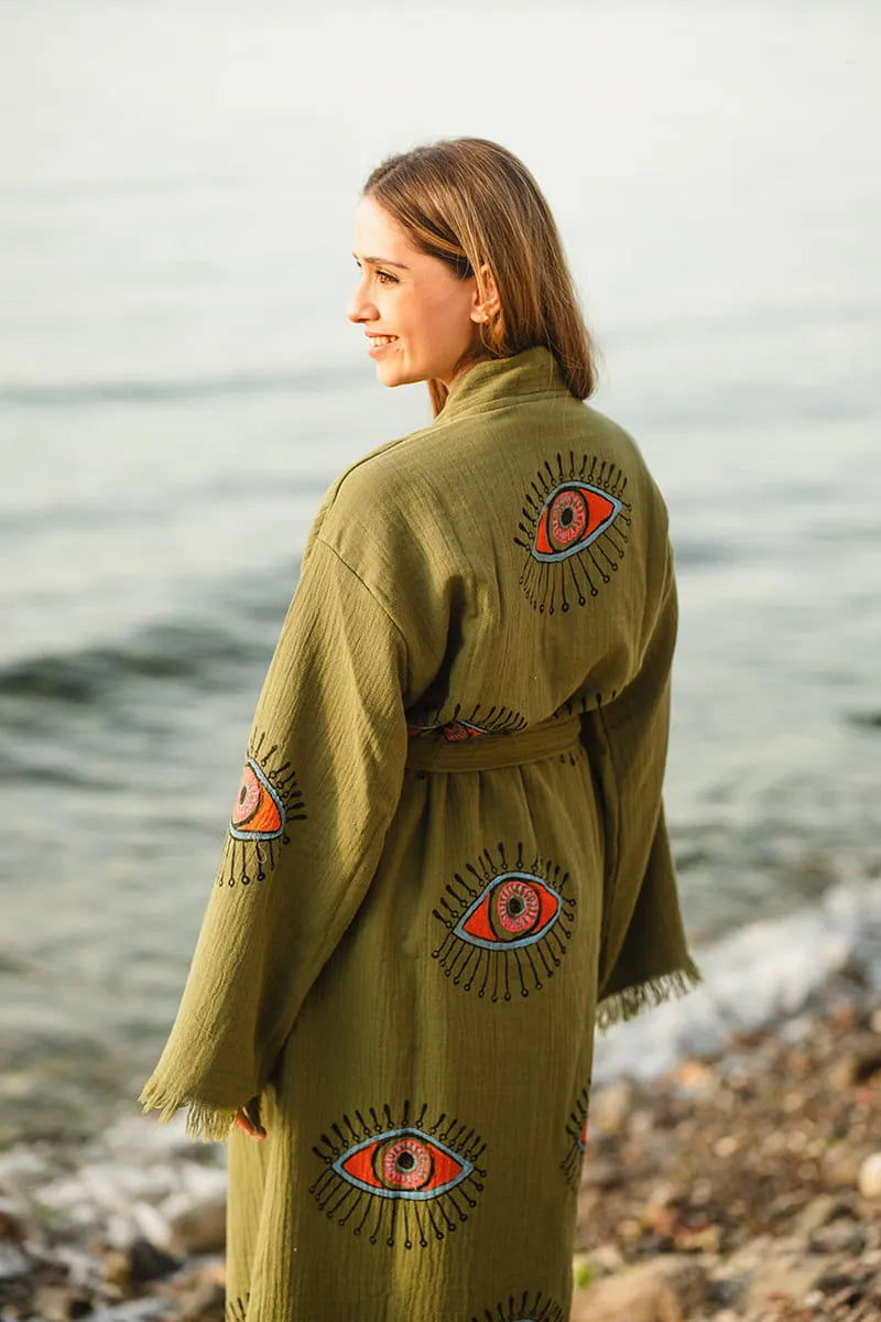Woman wearing a green kimono with eye designs by the water