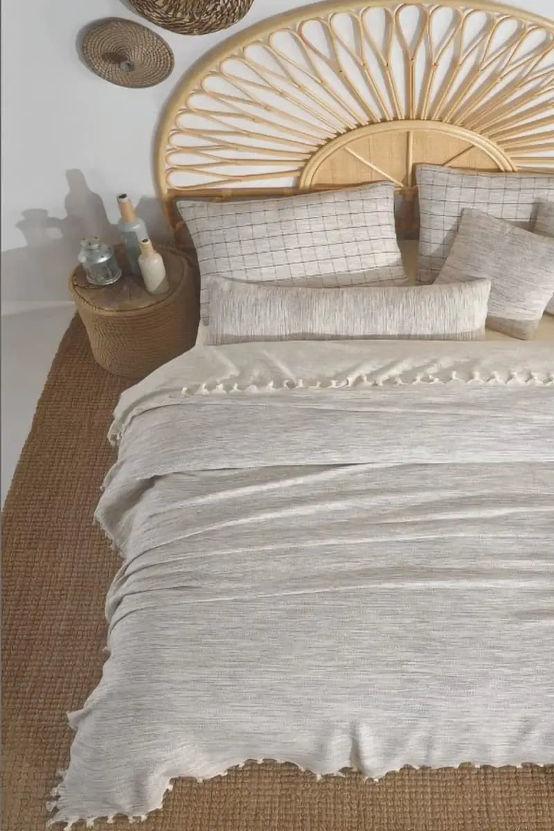 Bed with grey bedding and a wooden headboard in a bedroom setting.