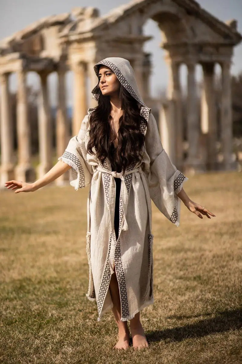Woman in a natural linen robe standing in front of ancient ruins