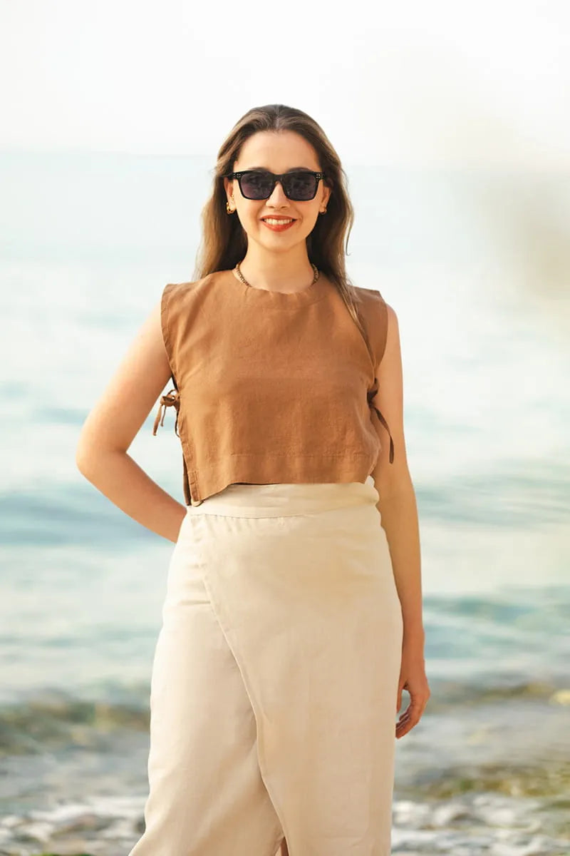 Woman wearing a brown sleeveless top and beige Linen Wrap Skirt standing on a beach.