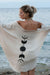 Woman standing on a beach wearing a beige cover-up with black moon phases design.