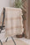 Mustard and cream striped cotton throw blanket draped over a chair with a plant. #Color_Mustard_Striped_Cream_Blanket