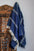 Navy blue striped throw blanket with tassels hanging on a wooden rack — organic cotton. #Color_White_Striped_Navy_Blue_Blanket
