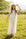 Woman in a white maxi dress and hat standing in a grassy field