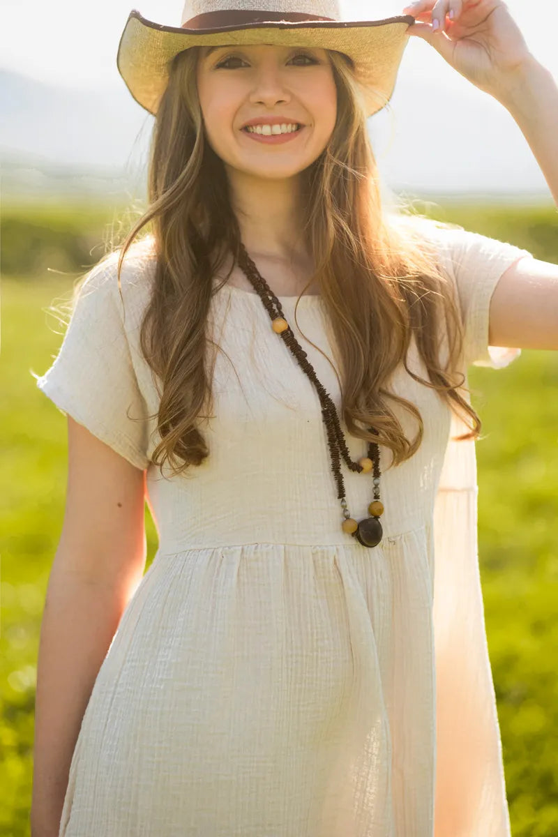 Young girl wearing a white Short Sleeve Empire Waist Maxi Dress and a straw hat in a field