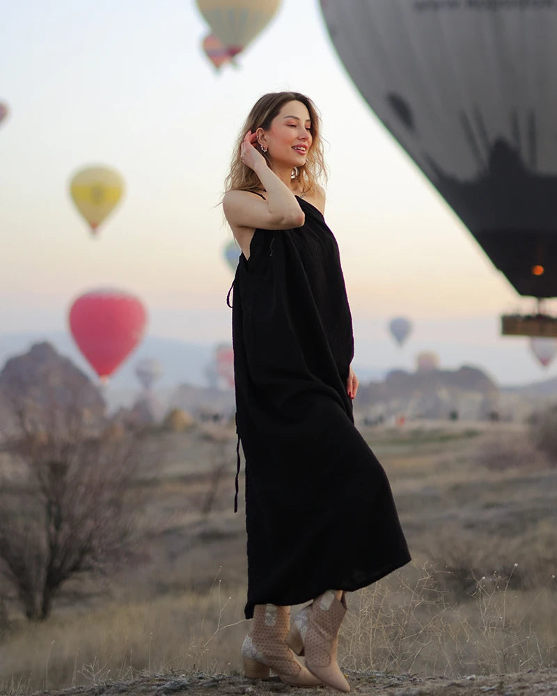 Woman in a black  muslin dress standing in front of hot air balloons
