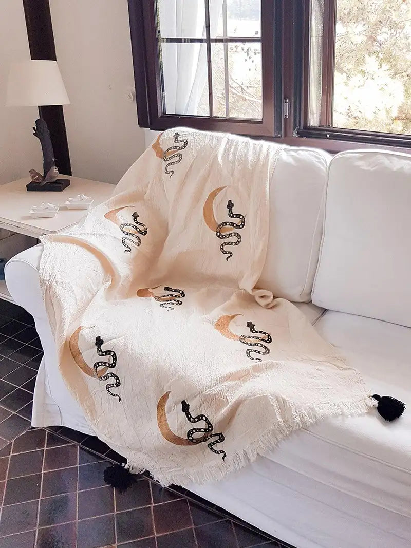White sofa with a decorative blanket featuring snake patterns in a living room setting.