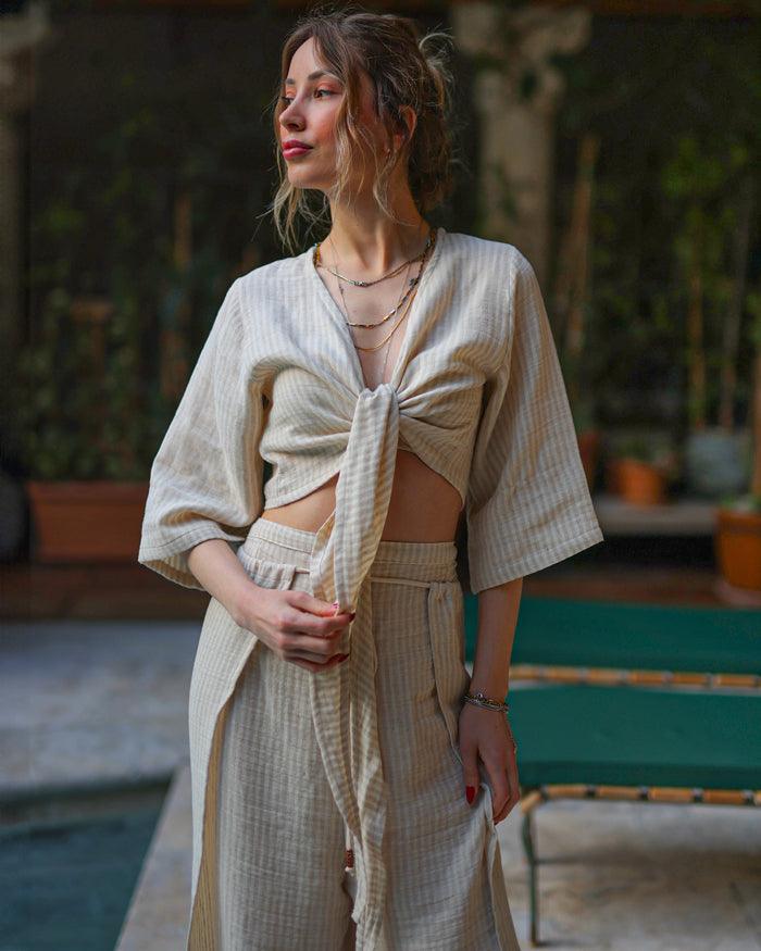 A woman wearing a beige striped front tie crop top and matching skirt.