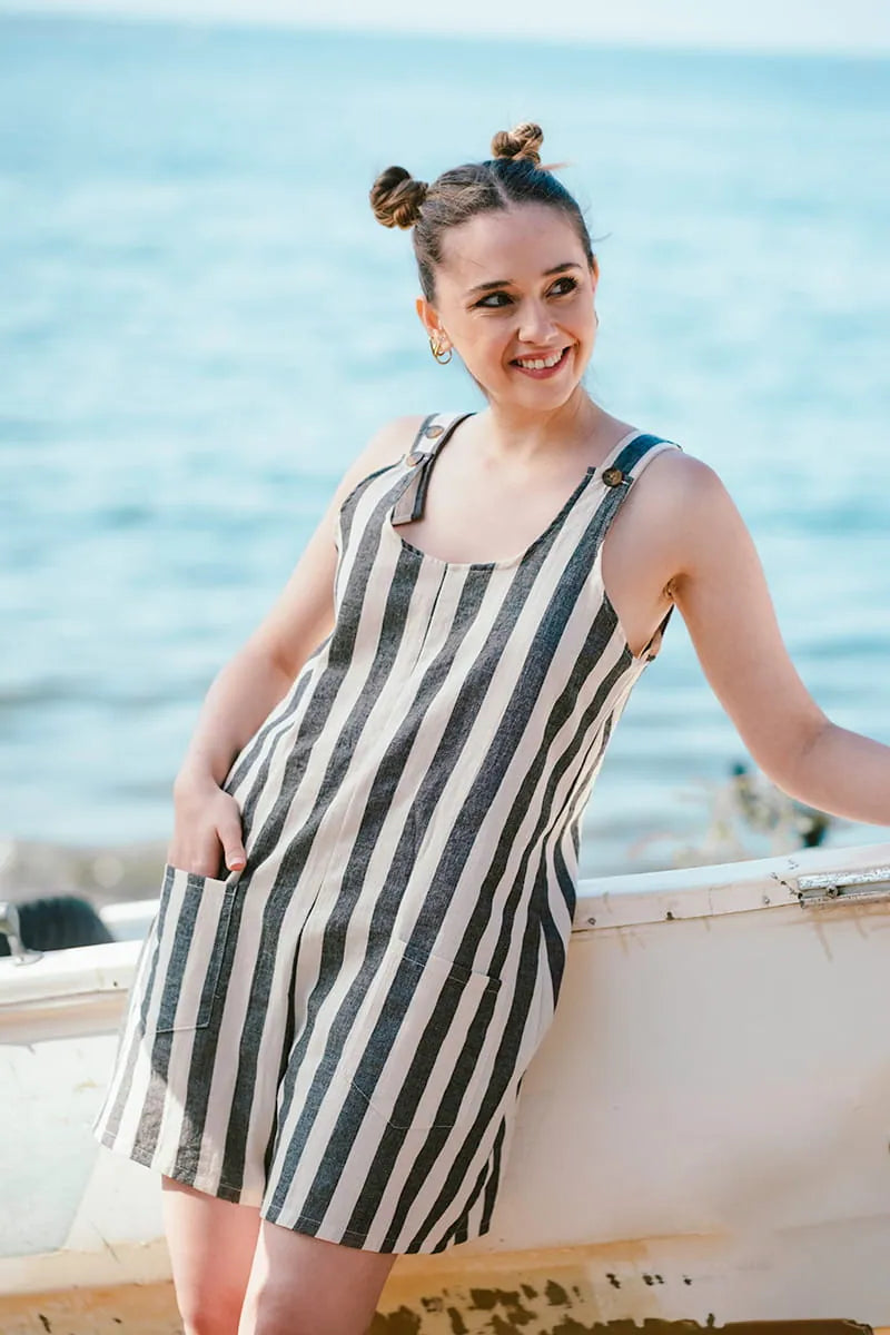 Woman in a striped romper standing on a boat with a blue sea background