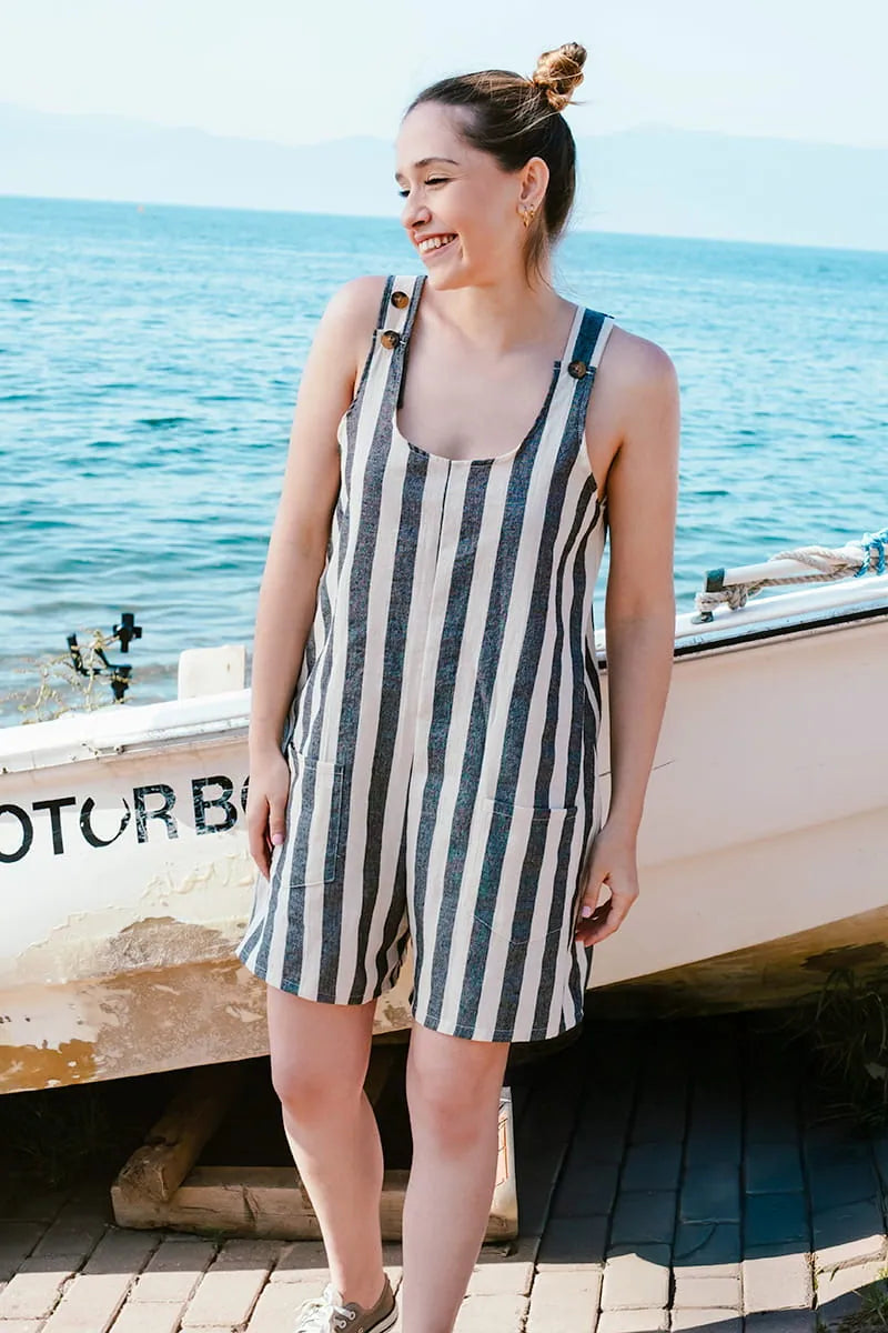 Woman in a striped Striped Linen Romper standing by a boat on a dock with water in the background