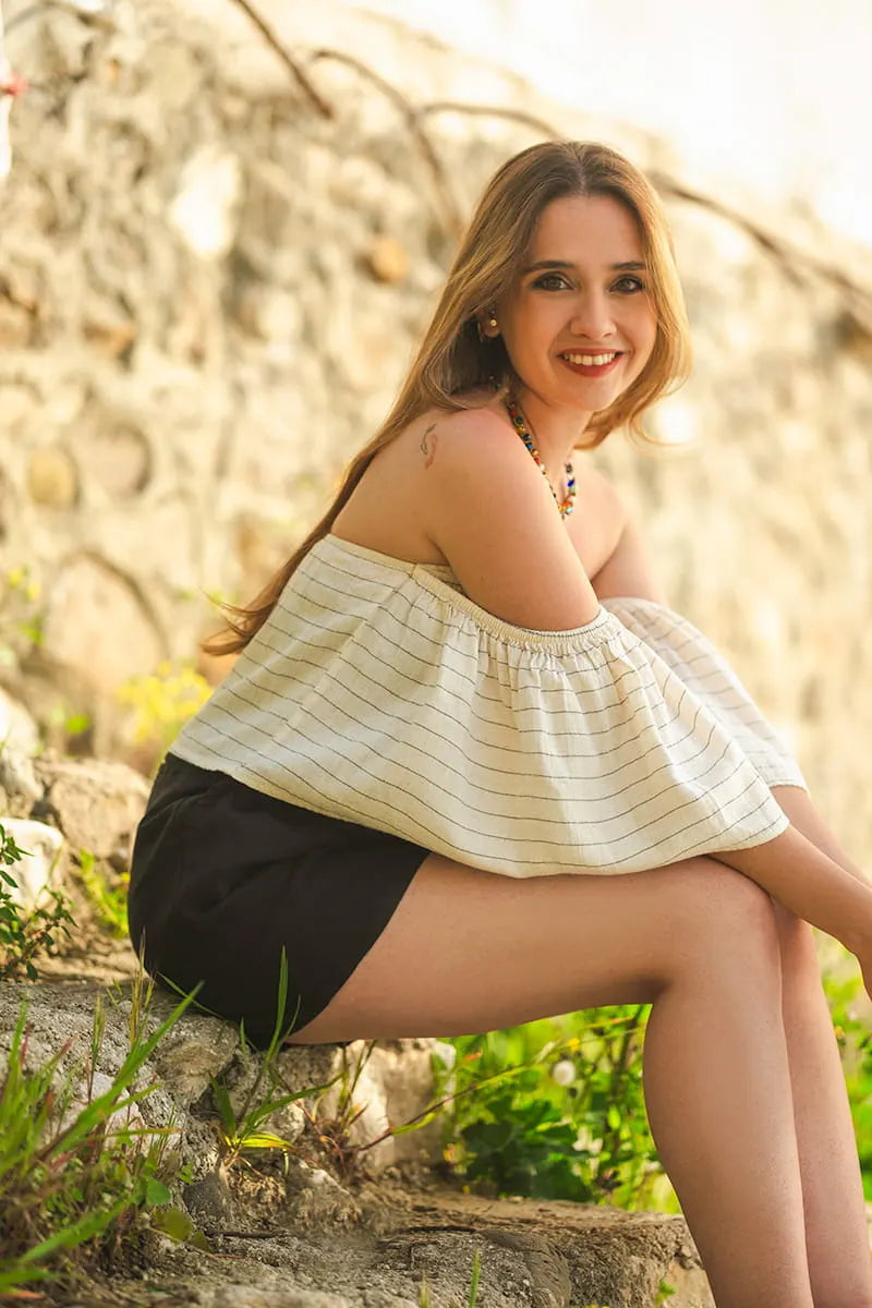 Woman sitting outdoors on a log with a blurred natural background