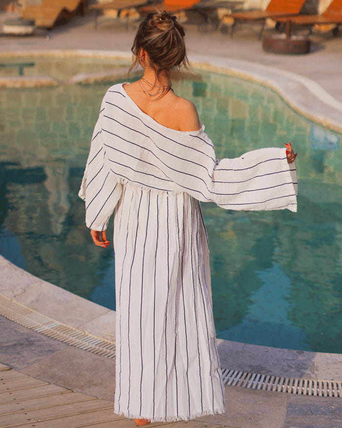 Woman in a striped skirt and striped off the shoulder top by a poolside