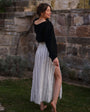 Woman in a black top and striped cotton maxi skirt by a stone wall — double gauze cotton, side slit