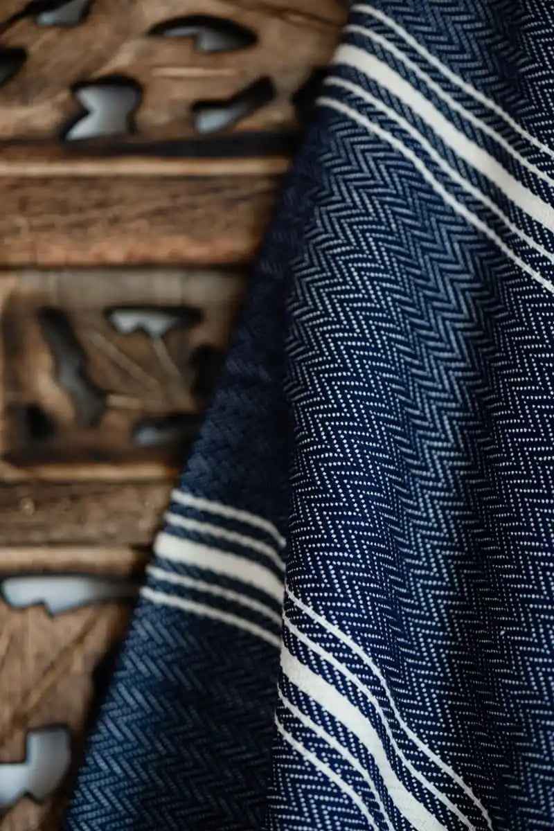 Close-up of a textured fabric with blue and white pattern next to wooden carvings.