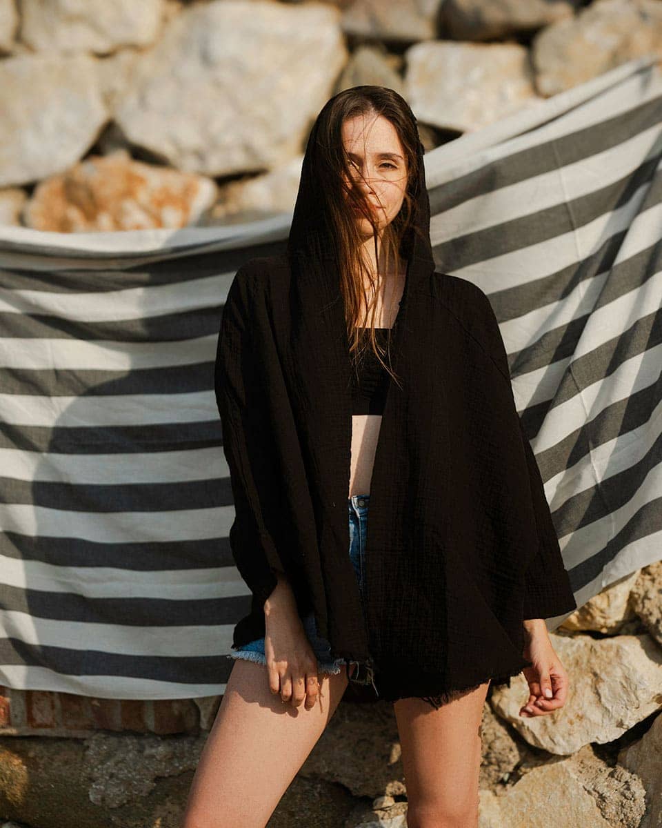 Woman standing in front of a stone wall with a open front hooded robe