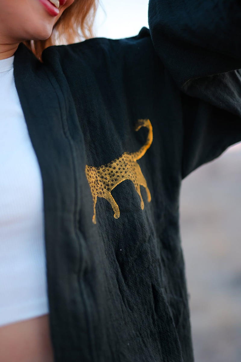Black jacket with a gold leopard print design on a blurred background