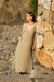 Woman in a V Neck Maxi Slip Dress standing against a stone wall on a rocky beach.