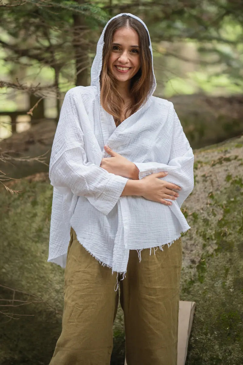 Woman wearing a white hooded muslin robe in a natural setting