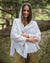 Woman wearing a white hooded poncho in a natural setting